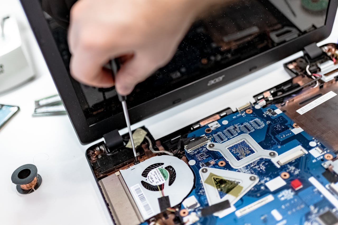 Offerings Technician repairing a laptop motherboard, focusing on electronic components.